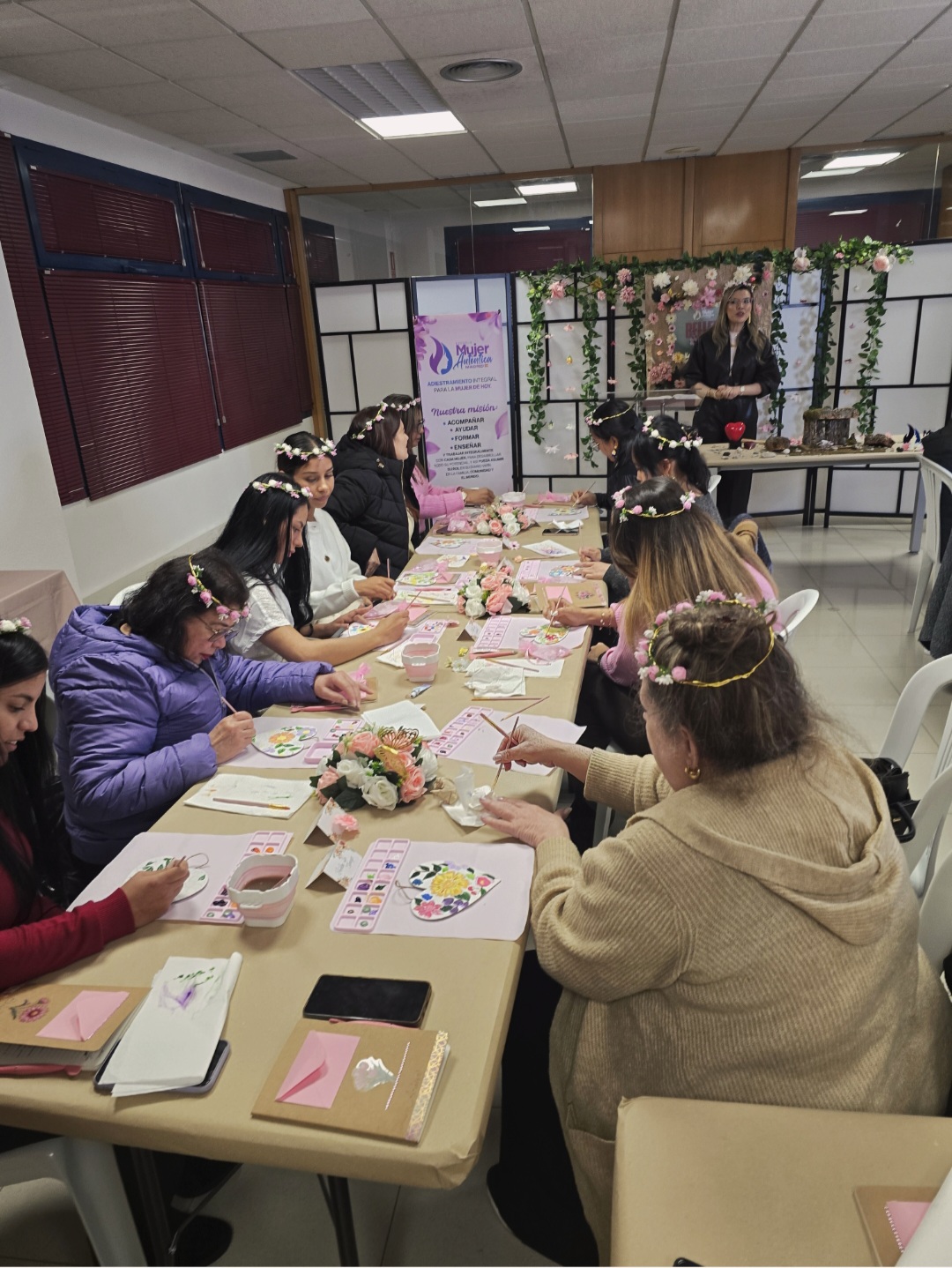 Mesa larga con mujeres pintando corazones de flores