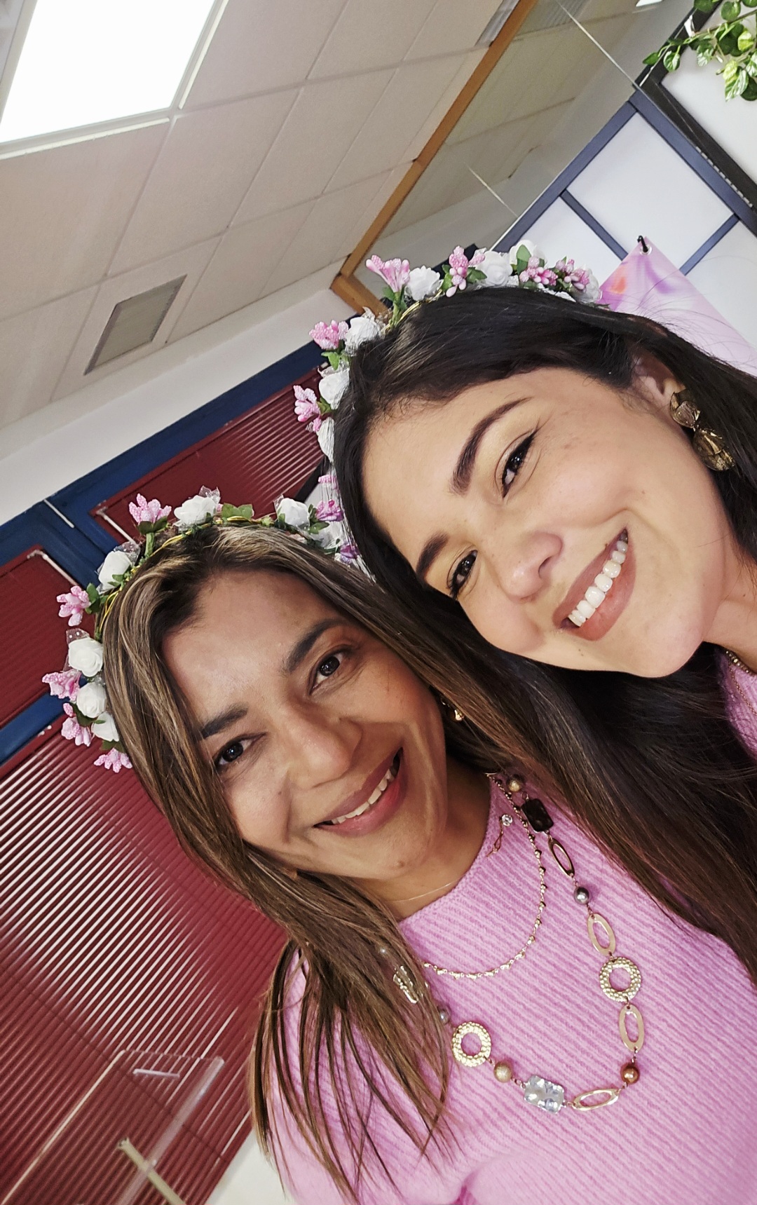 Dos asistentes sonriendo con coronas de flores